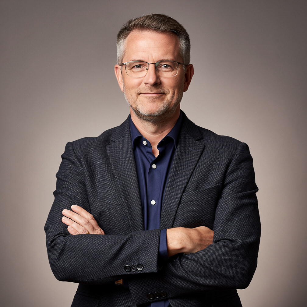 Studio portrait of a white British man in his 50s wearing glasses
